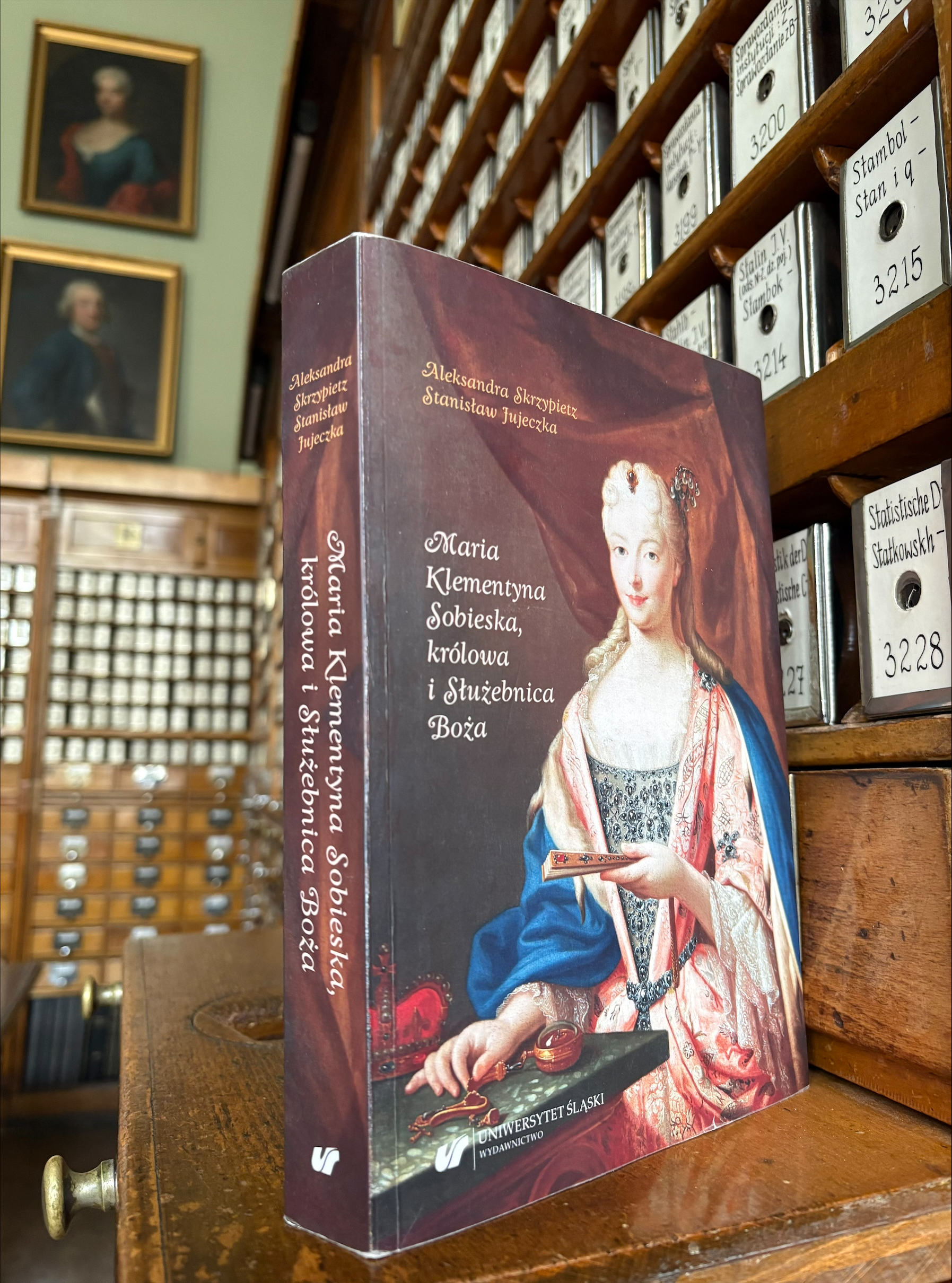 Okłądka książki na tle katalogu bibliotecznego